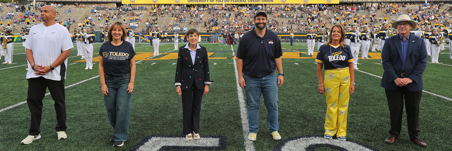alumni honorees at homecoming halftime, flanked by Billy Pierce and Dr. James Holloway